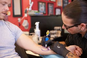 Tattoo Artist Working On Design For Male Client